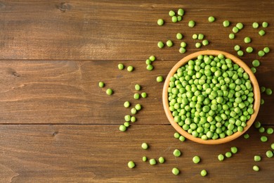 Photo of Fresh green peas in bowl on wooden table, top view. Space for text