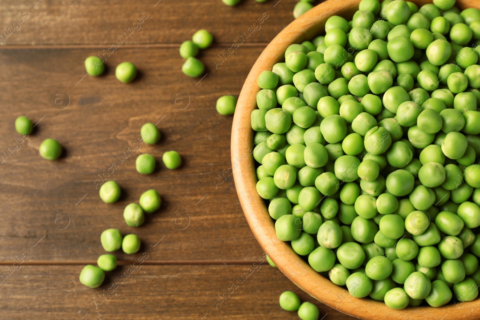 Photo of Fresh green peas in bowl on wooden table, above view. Space for text