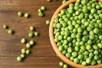 Photo of Fresh green peas in bowl on wooden table, above view. Space for text