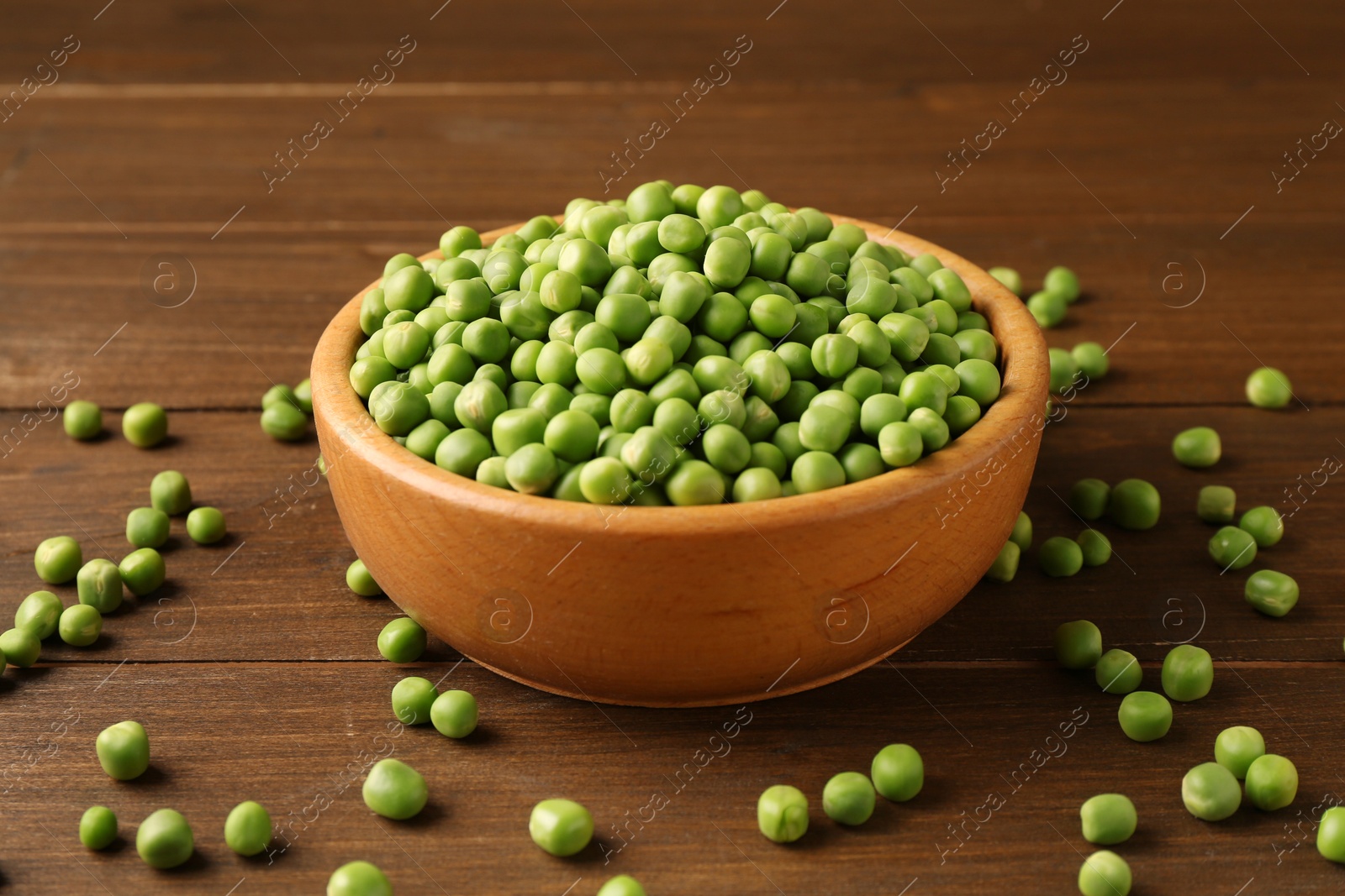 Photo of Fresh green peas in bowl on wooden table