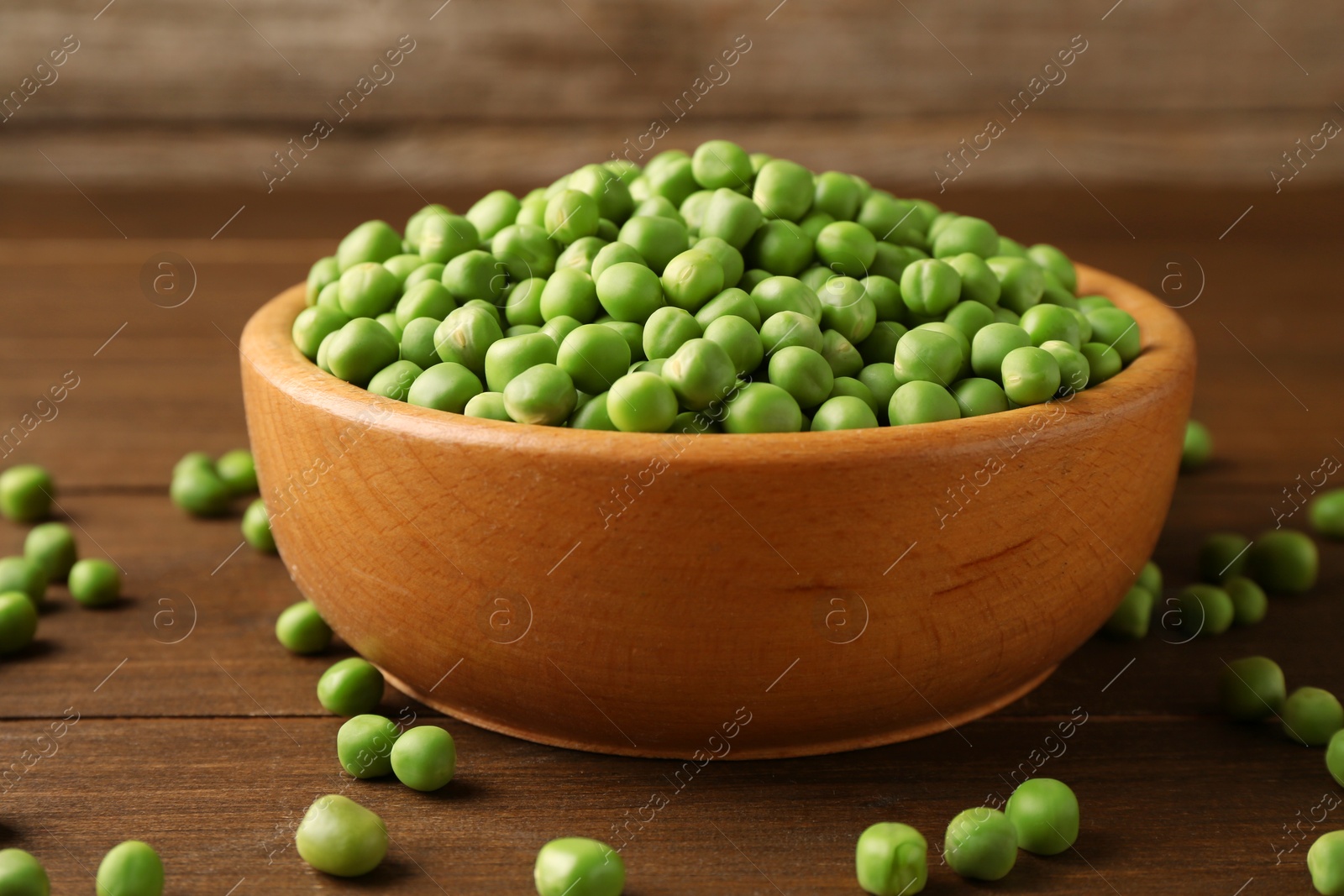 Photo of Fresh green peas in bowl on wooden table, closeup