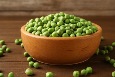 Photo of Fresh green peas in bowl on wooden table, closeup