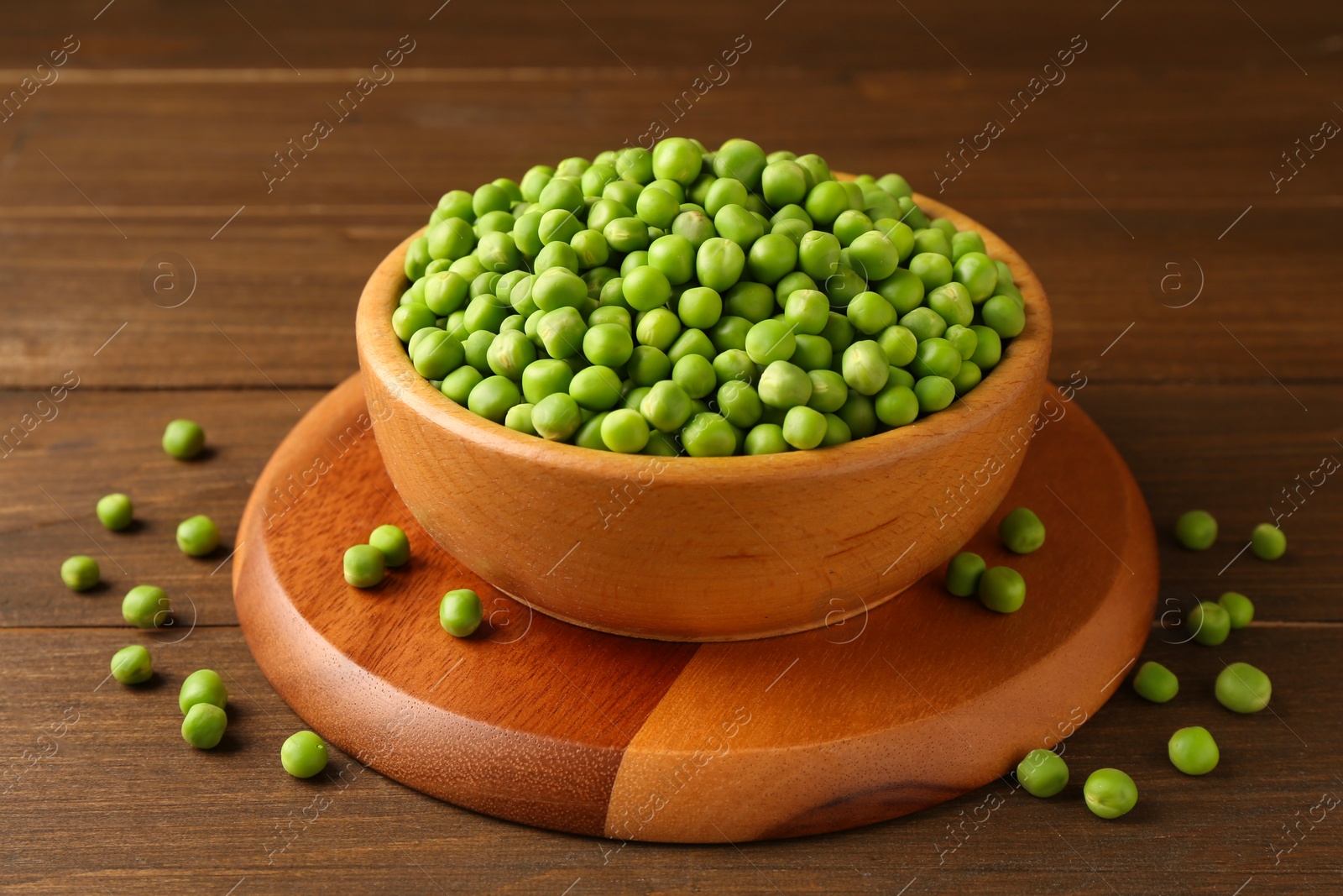 Photo of Fresh green peas in bowl on wooden table