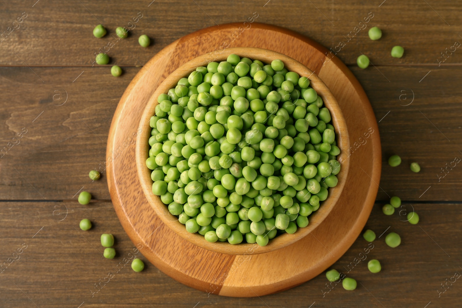 Photo of Fresh green peas in bowl on wooden table, top view