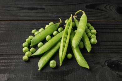 Photo of Fresh green peas and pods on black wooden table