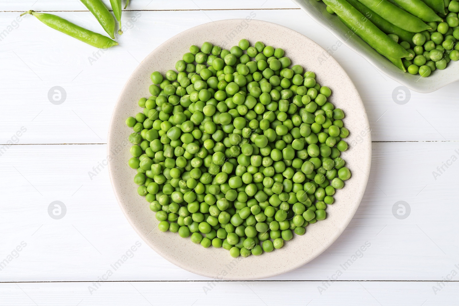 Photo of Fresh green peas and pods on white wooden table, flat lay