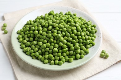 Photo of Fresh green peas in plate on white wooden table