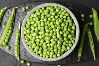 Photo of Fresh green peas and pods on black table, flat lay