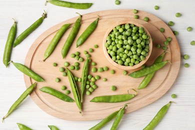 Photo of Fresh green peas and pods on white wooden table, flat lay