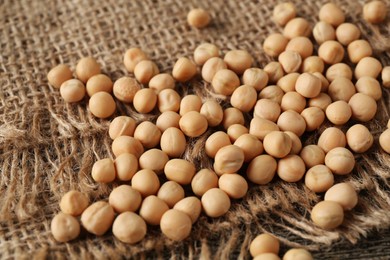 Many dried peas on burlap fabric, closeup