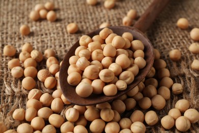 Photo of Spoon with dried peas on burlap fabric, closeup