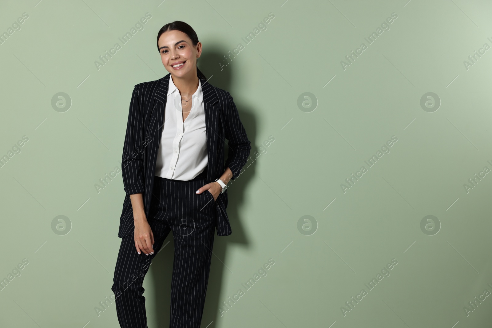 Photo of Beautiful woman in black striped suit on green background, space for text