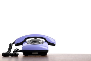 Photo of One violet telephone with handset on wooden table against white background