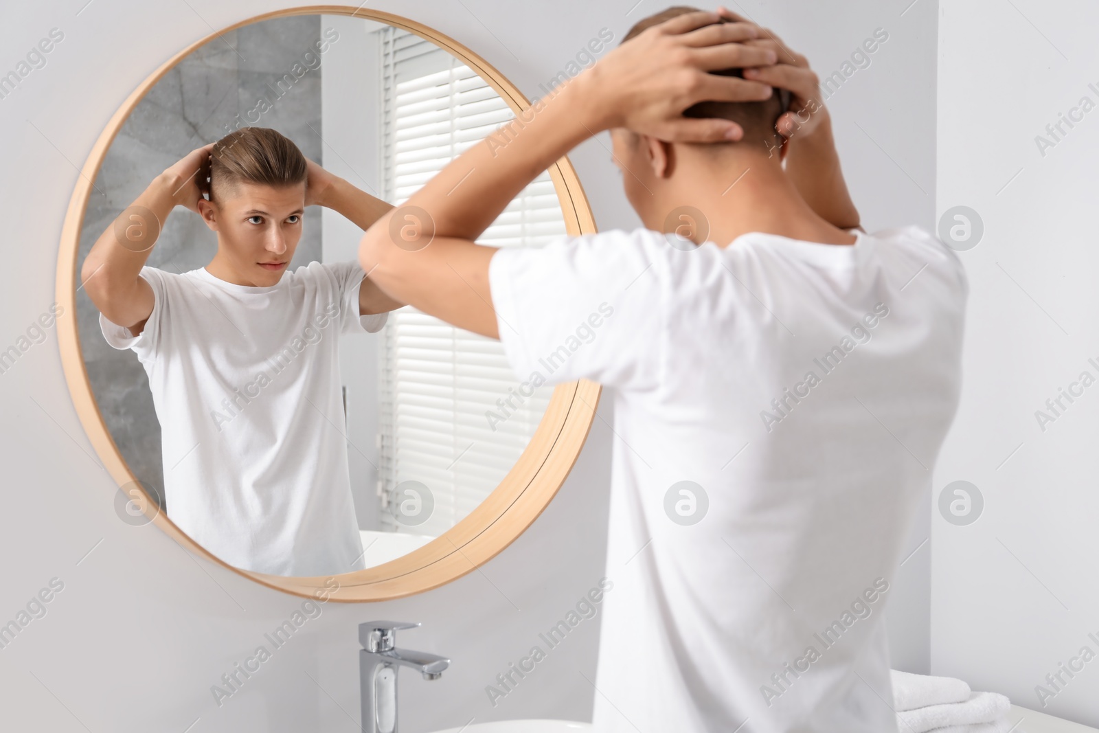 Photo of Handsome man looking at mirror in bathroom