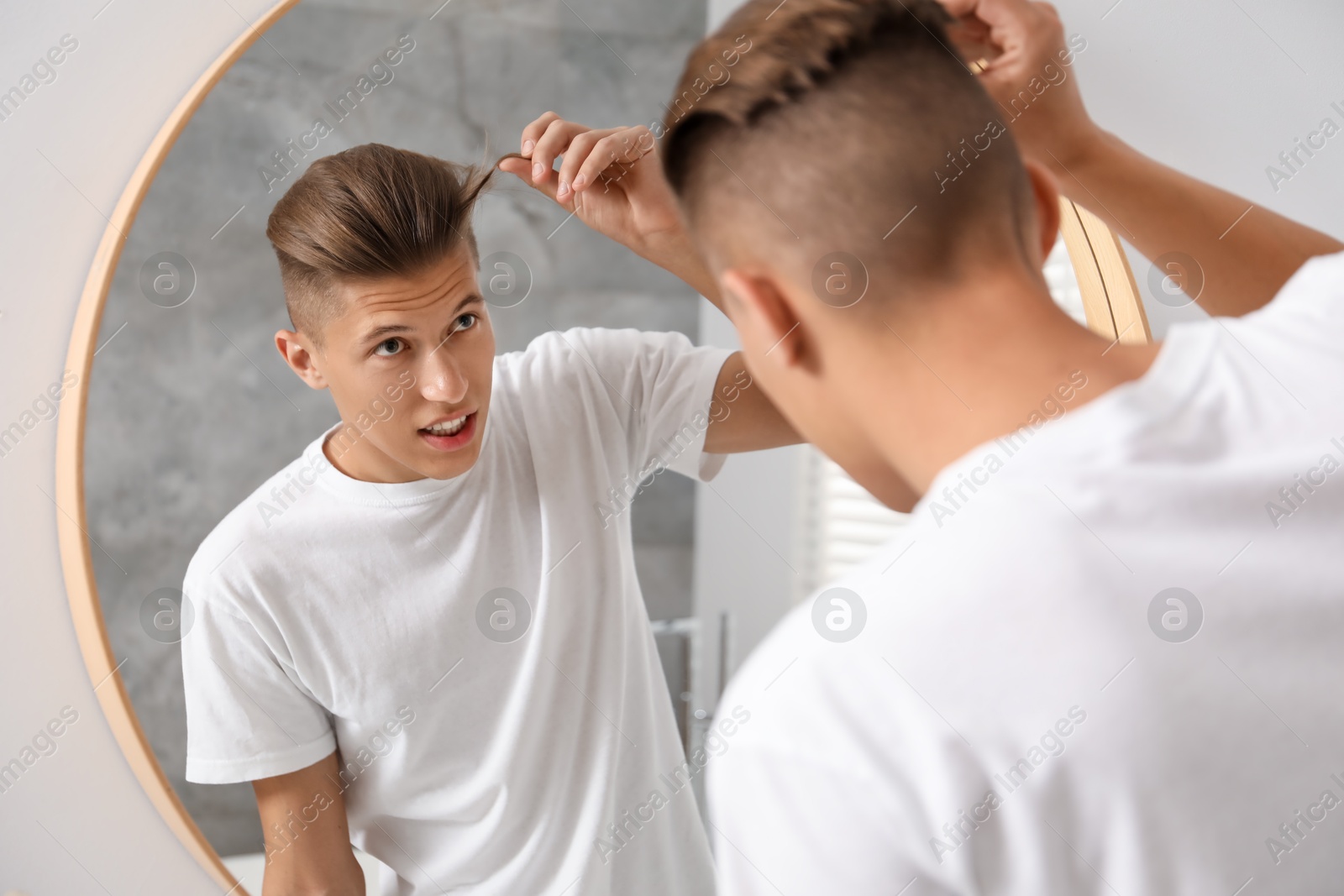 Photo of Handsome man looking at mirror in bathroom