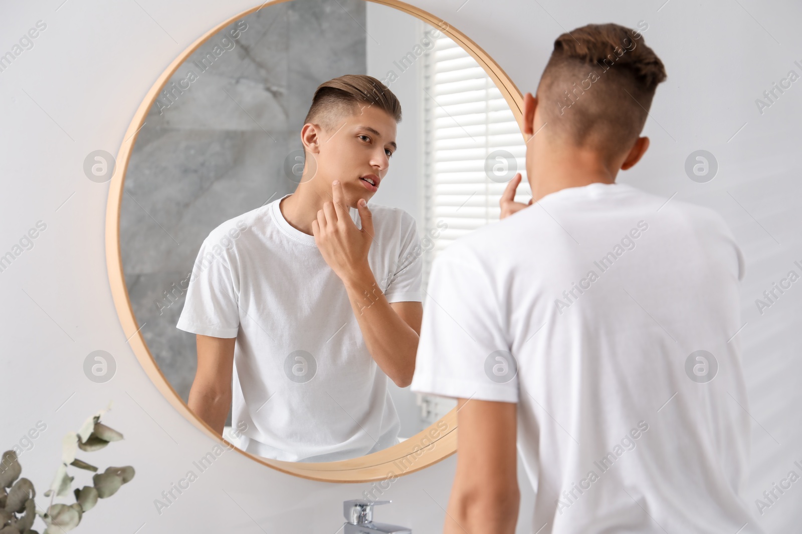 Photo of Man touching his face near mirror in bathroom