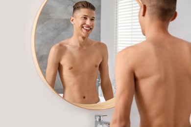 Photo of Handsome man looking at mirror in bathroom