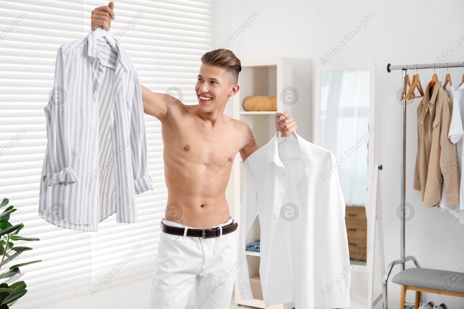 Photo of Handsome young man choosing clothes at home