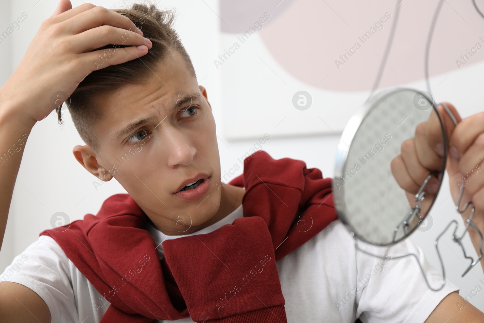 Photo of Man with mirror examining his head indoors