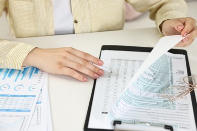 Budget planning. Woman with papers at white table, closeup