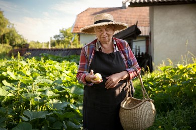 Photo of Senior farmer with wicker basket in garden