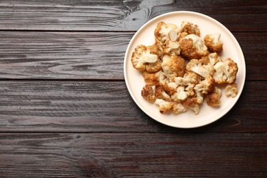 Photo of Plate with tasty baked cauliflower on wooden table, top view. Space for text