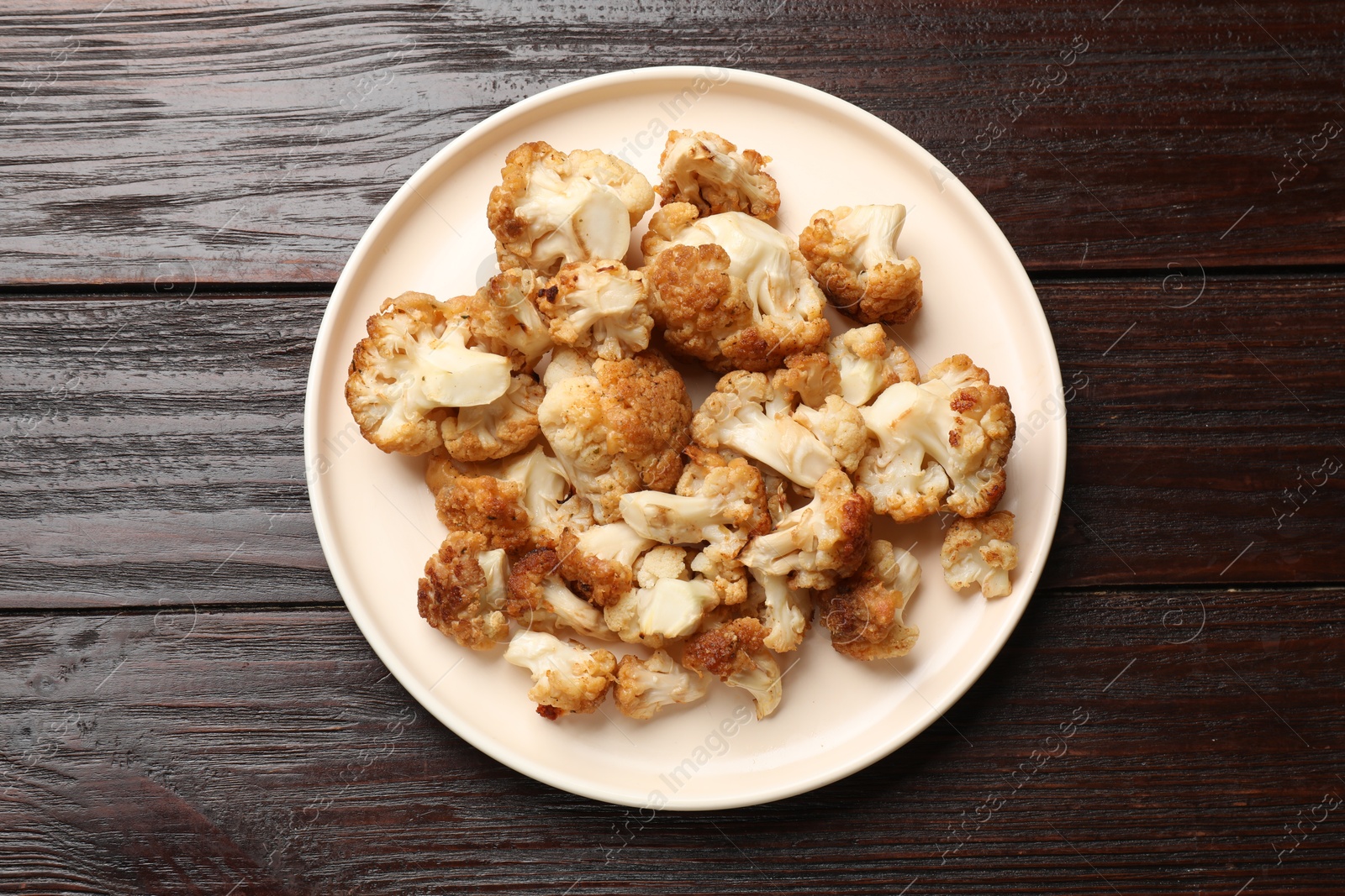 Photo of Plate with tasty baked cauliflower on wooden table, top view