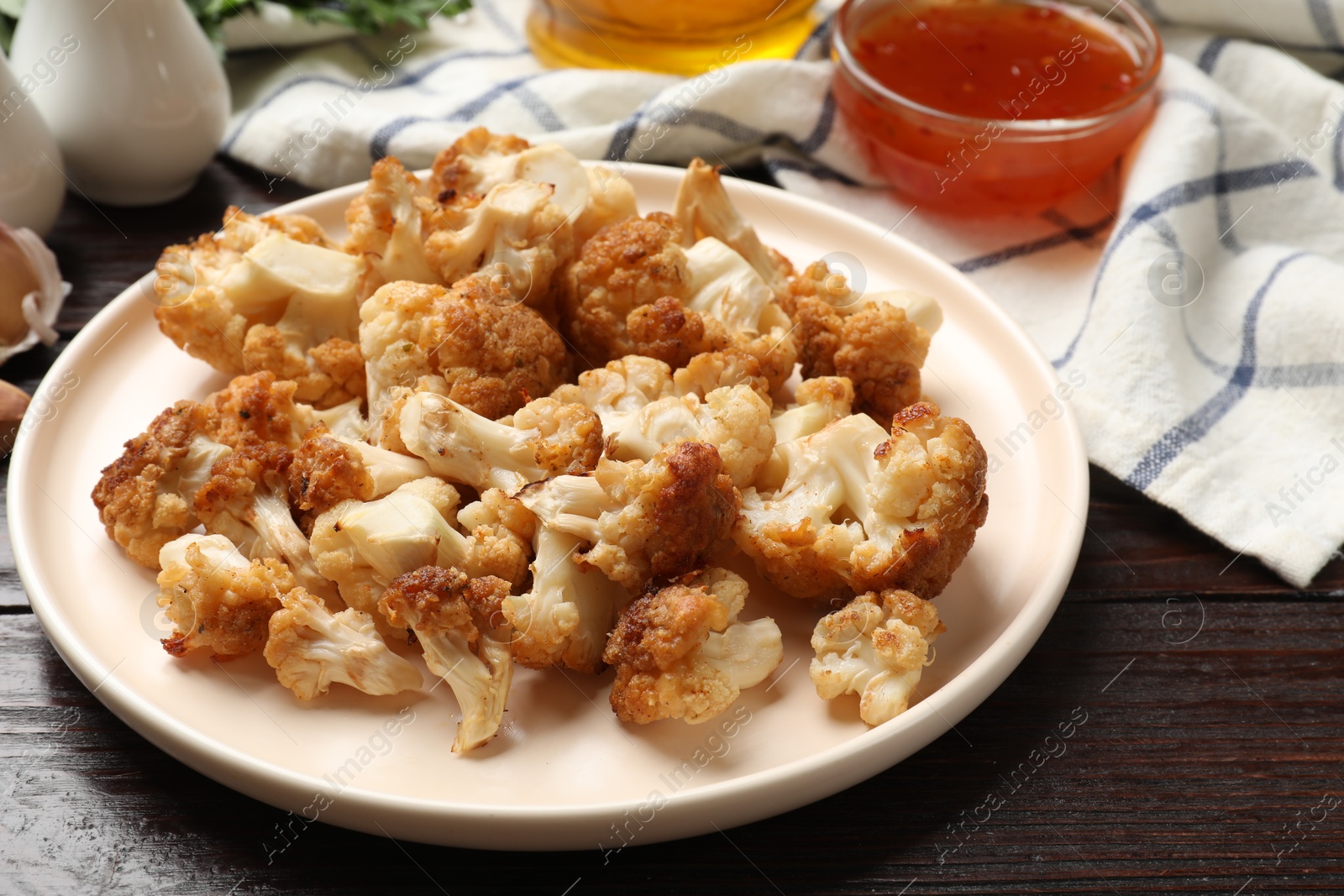 Photo of Plate with tasty baked cauliflower on wooden table, closeup