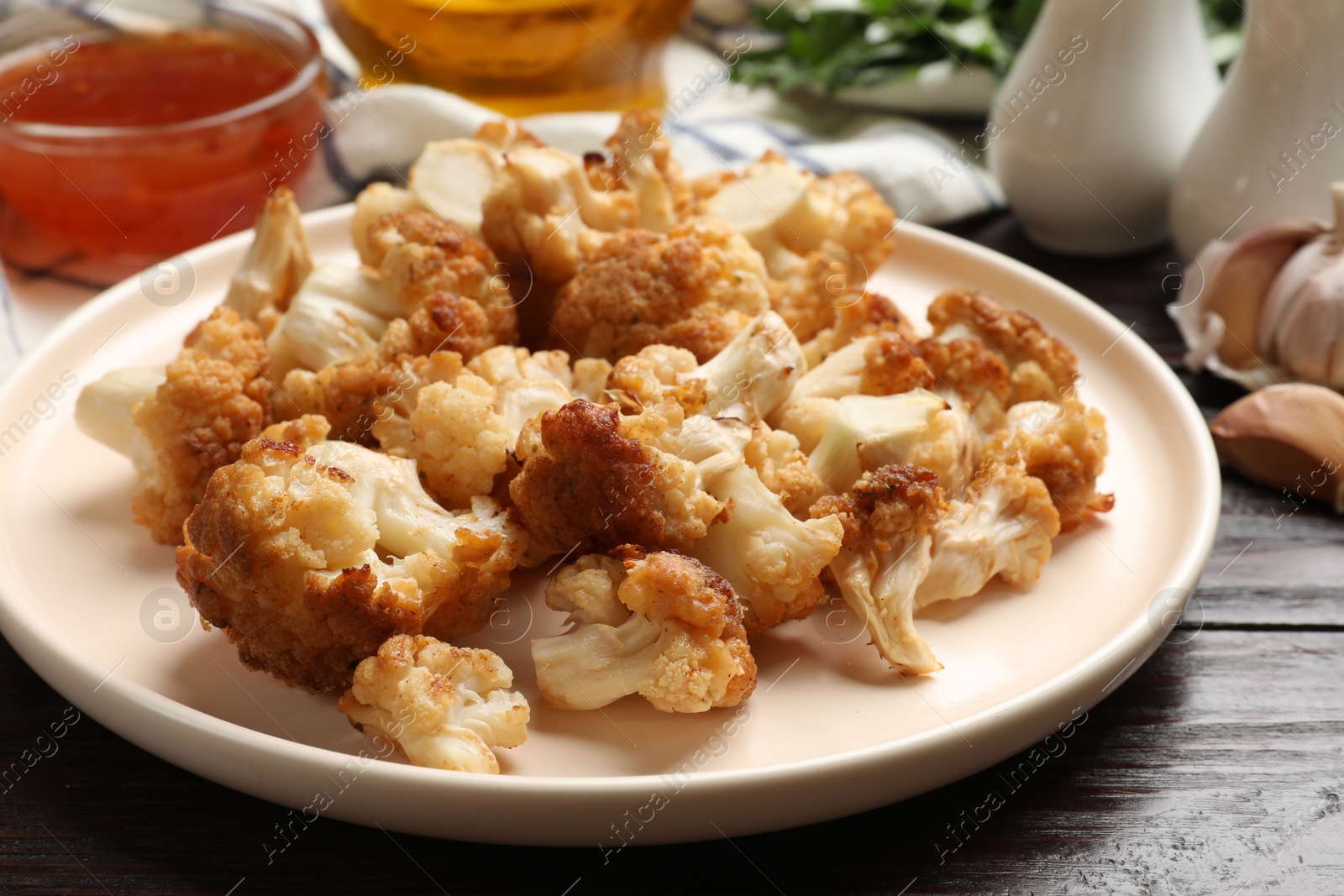 Photo of Plate with tasty baked cauliflower on wooden table, closeup