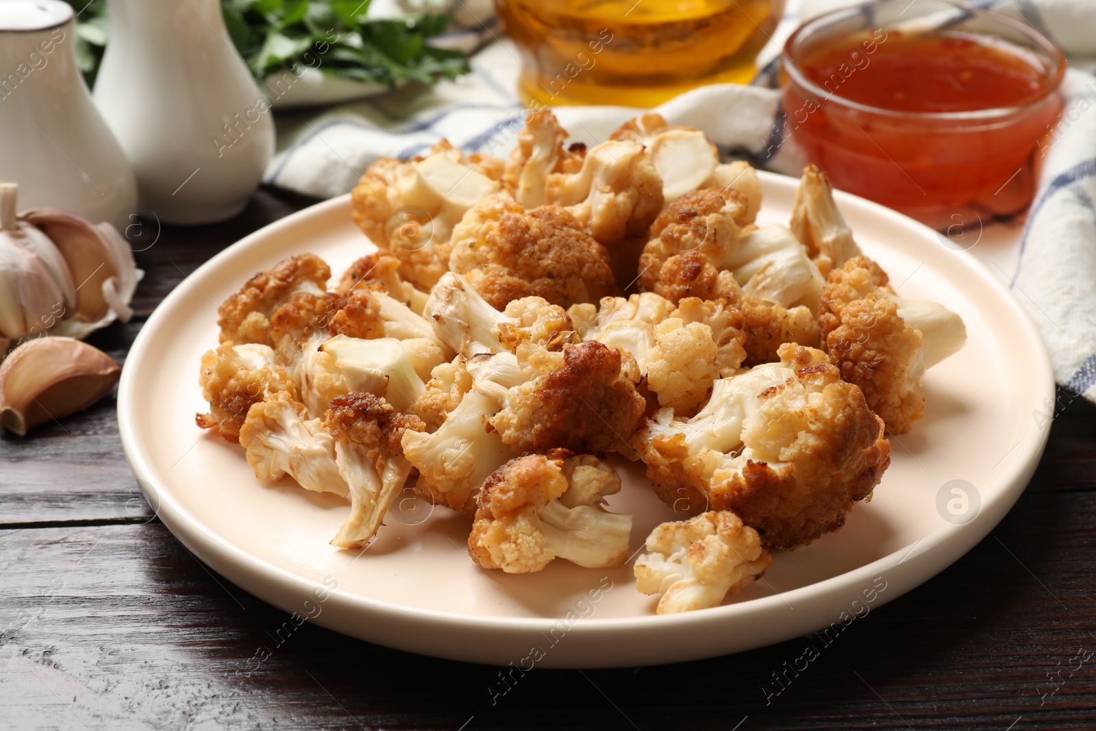 Photo of Plate with tasty baked cauliflower on wooden table, closeup