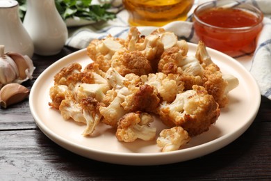 Plate with tasty baked cauliflower on wooden table, closeup