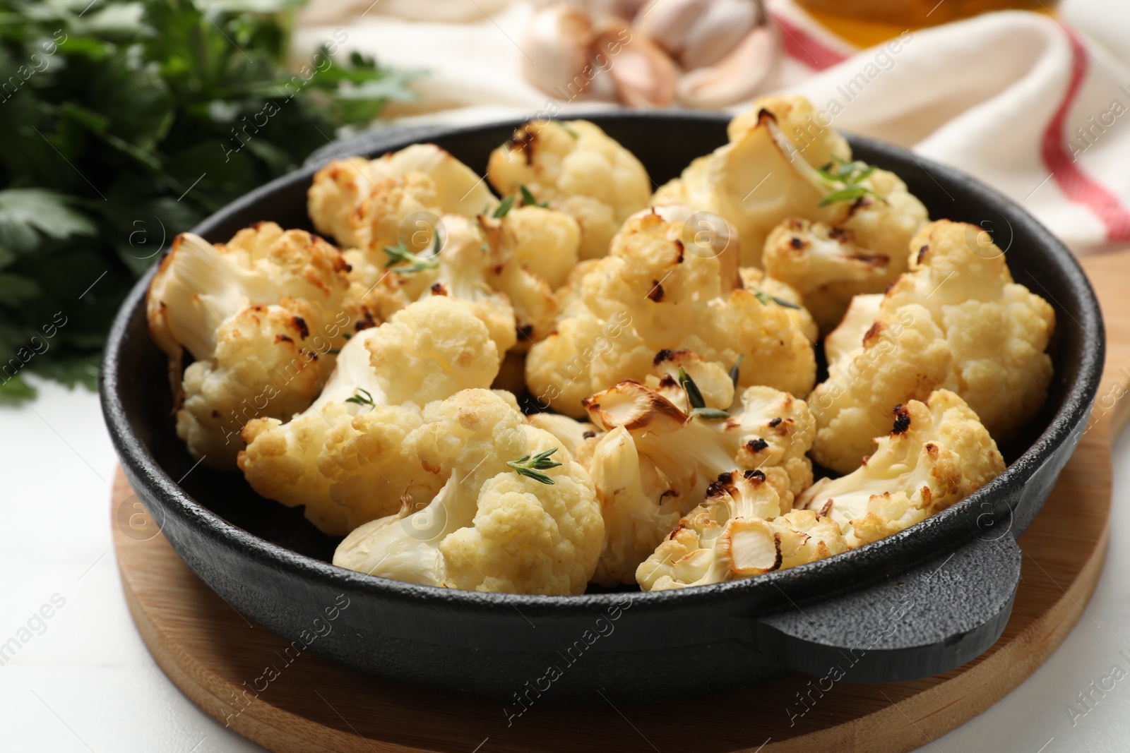 Photo of Tasty baked cauliflower in baking pan on white table, closeup