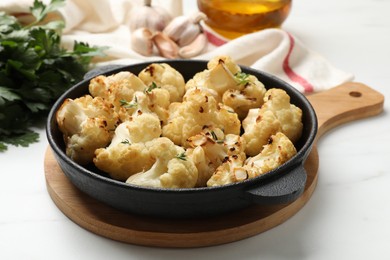 Photo of Tasty baked cauliflower in baking pan on white table, closeup