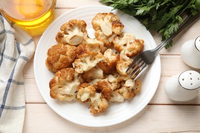 Plate with tasty baked cauliflower served on light wooden table, flat lay