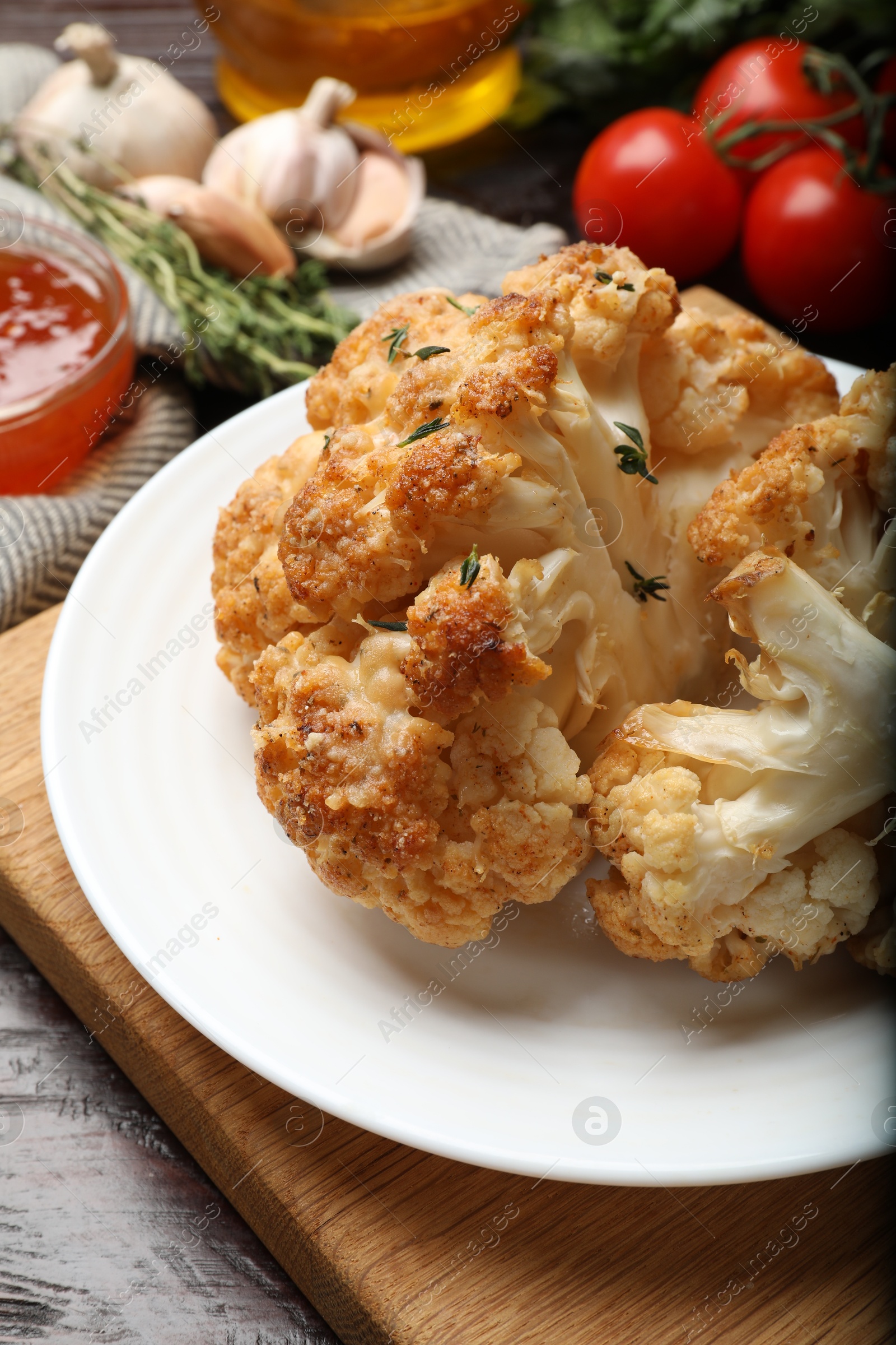 Photo of Plate with tasty baked cauliflower on wooden table, closeup