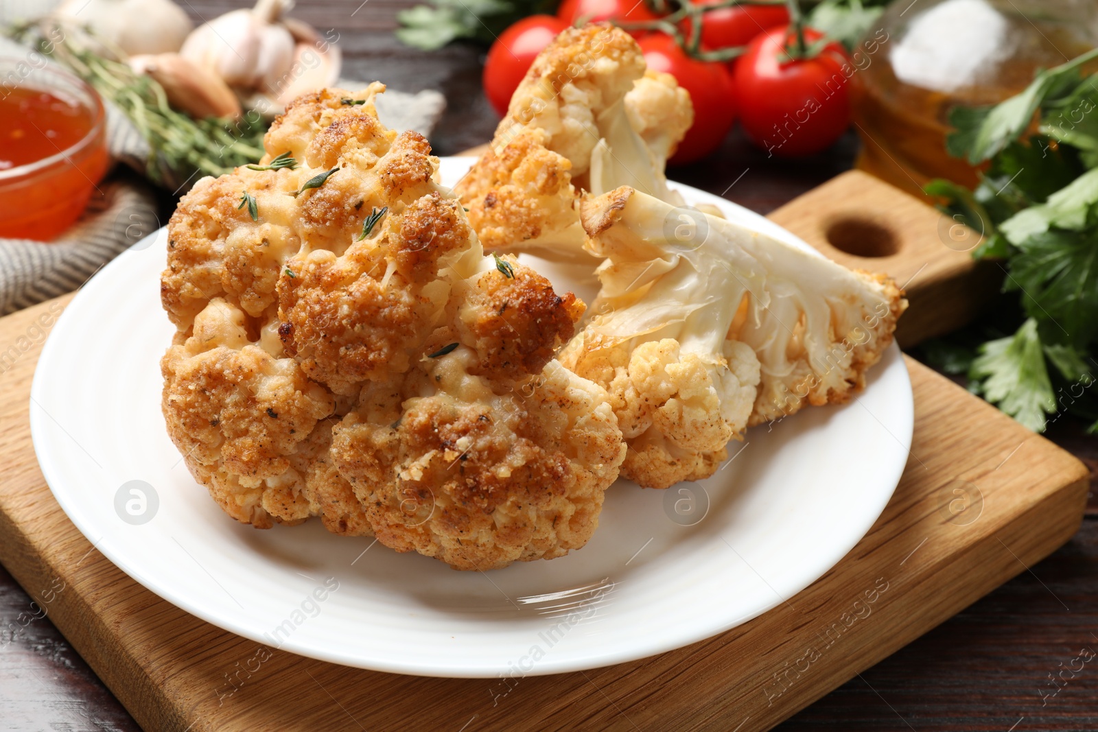 Photo of Plate with tasty baked cauliflower on wooden table, closeup