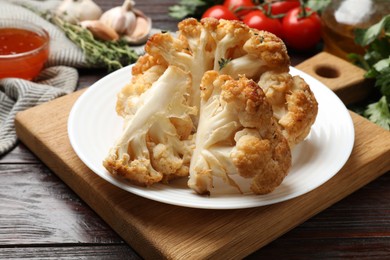 Plate with tasty baked cauliflower on wooden table, closeup