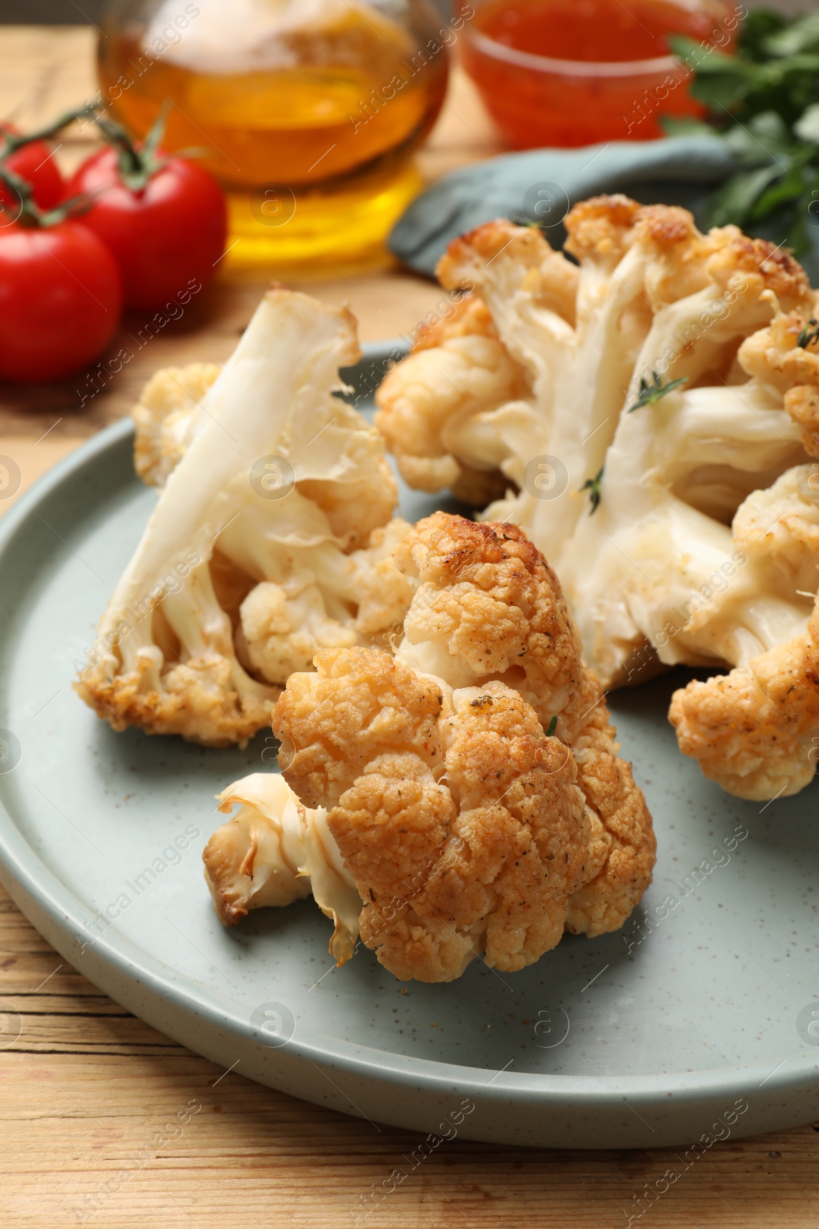 Photo of Plate with tasty baked cauliflower on wooden table, closeup