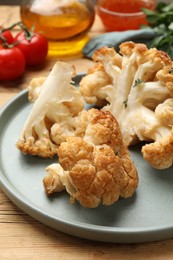 Plate with tasty baked cauliflower on wooden table, closeup