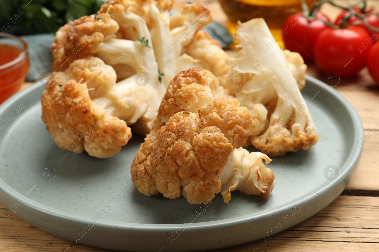 Photo of Plate with tasty baked cauliflower on wooden table, closeup