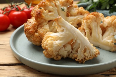 Photo of Plate with tasty baked cauliflower on wooden table, closeup