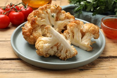 Photo of Plate with tasty baked cauliflower on wooden table, closeup