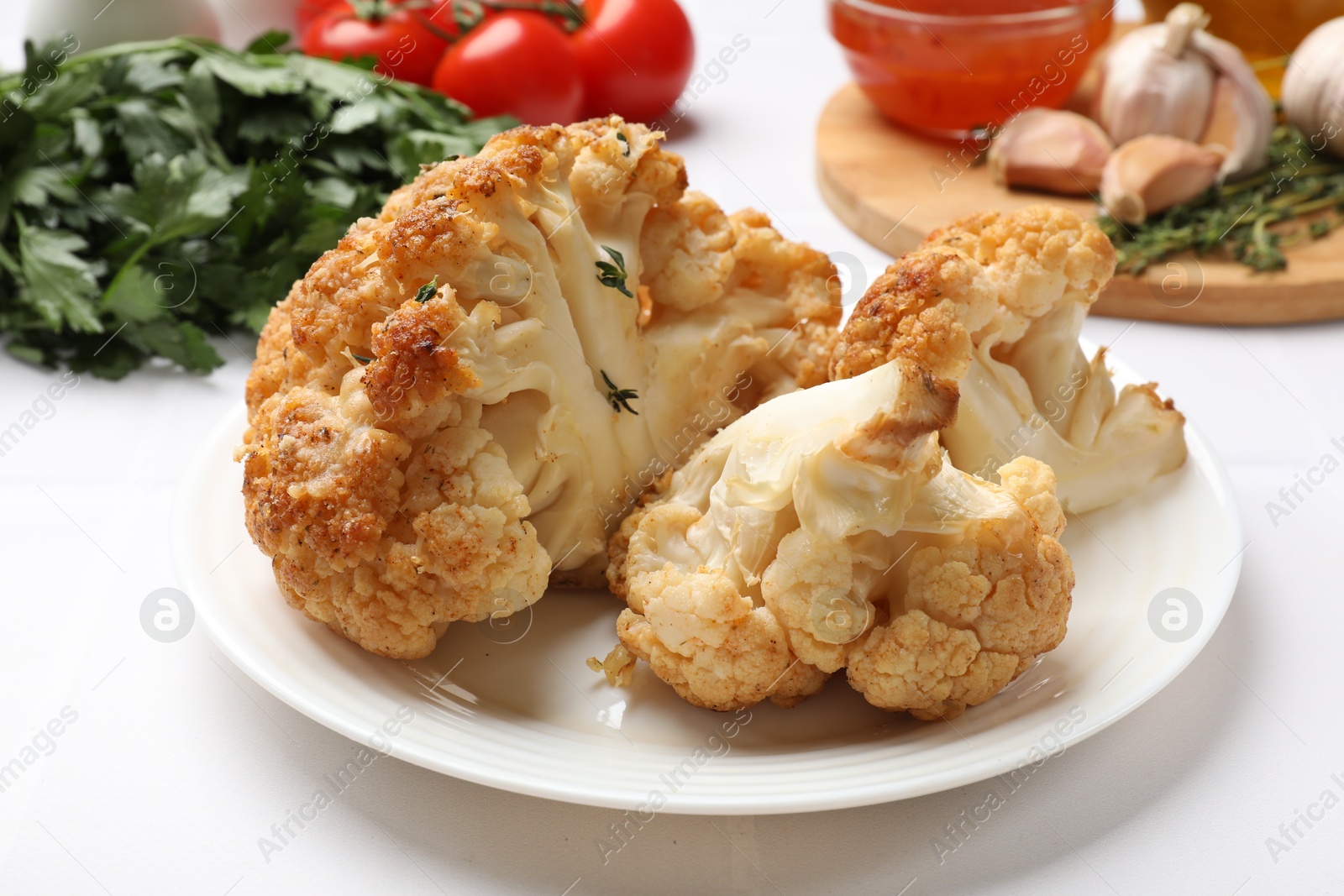 Photo of Plate with tasty baked cauliflower on white table, closeup