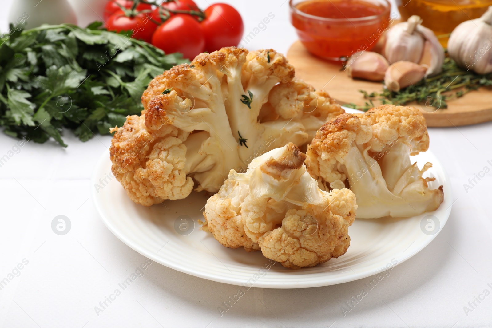 Photo of Plate with tasty baked cauliflower on white table, closeup