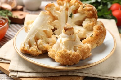 Photo of Plate with tasty baked cauliflower on table, closeup