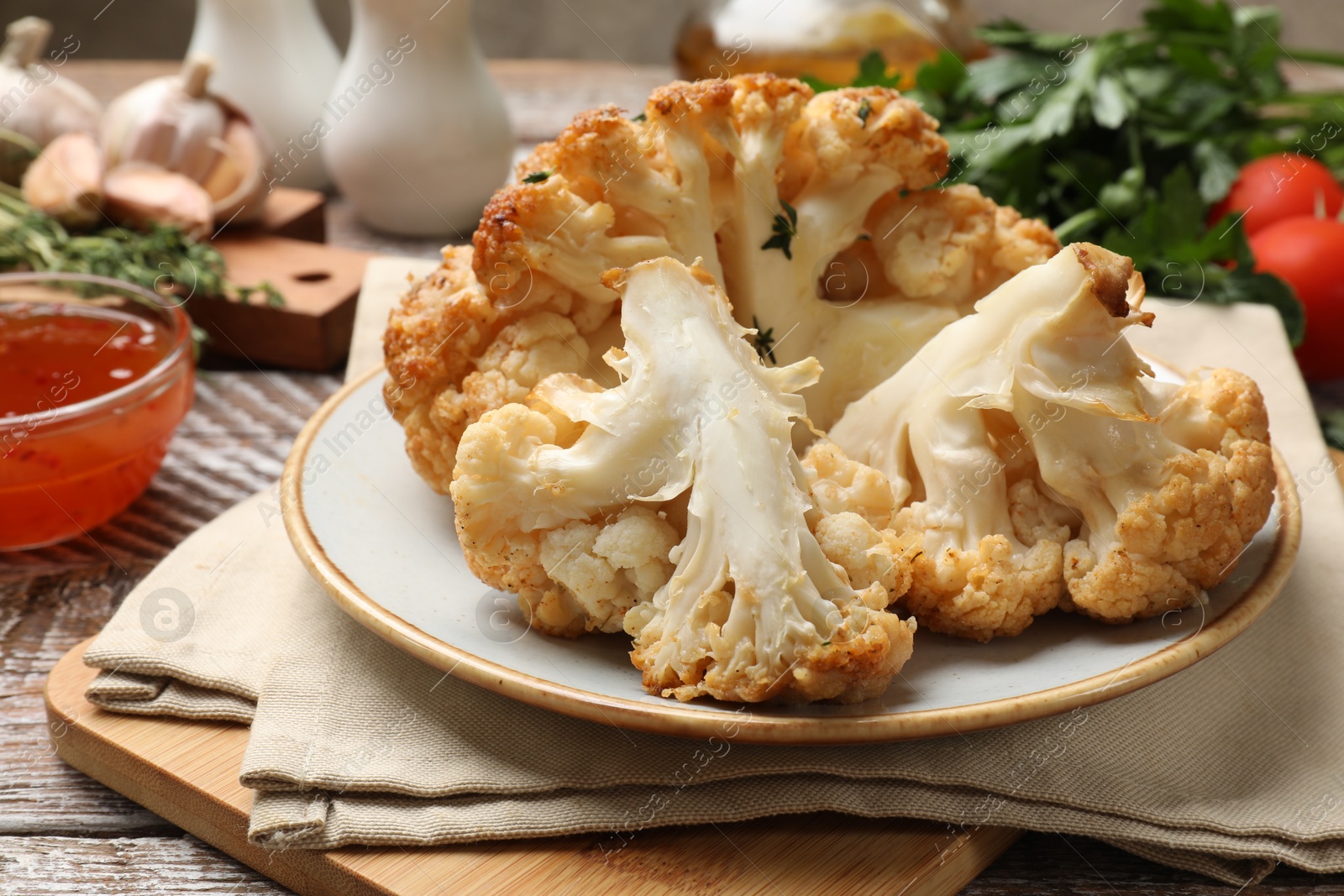 Photo of Plate with tasty baked cauliflower on wooden table, closeup