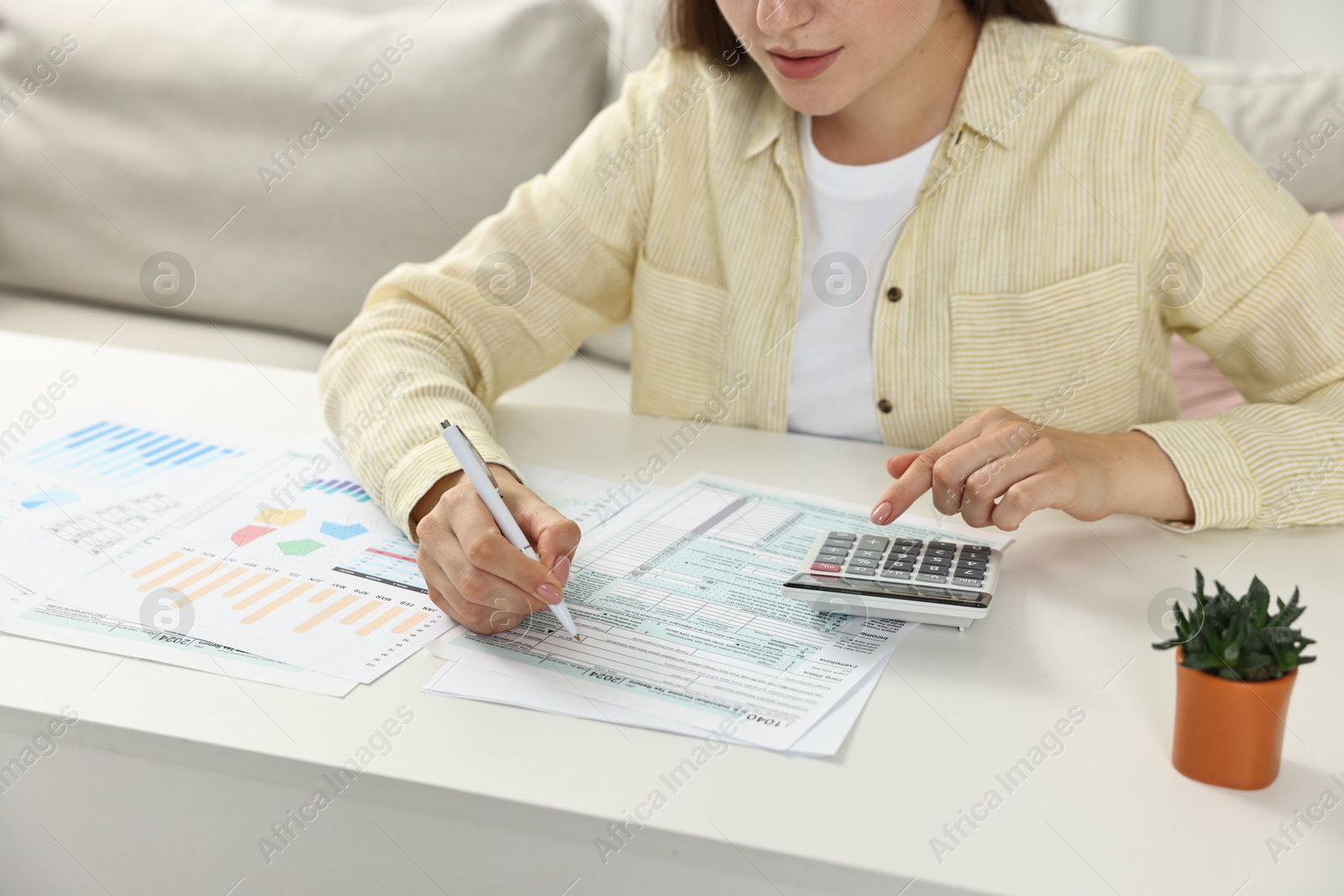 Photo of Budget planning. Woman with papers using calculator at white table, closeup