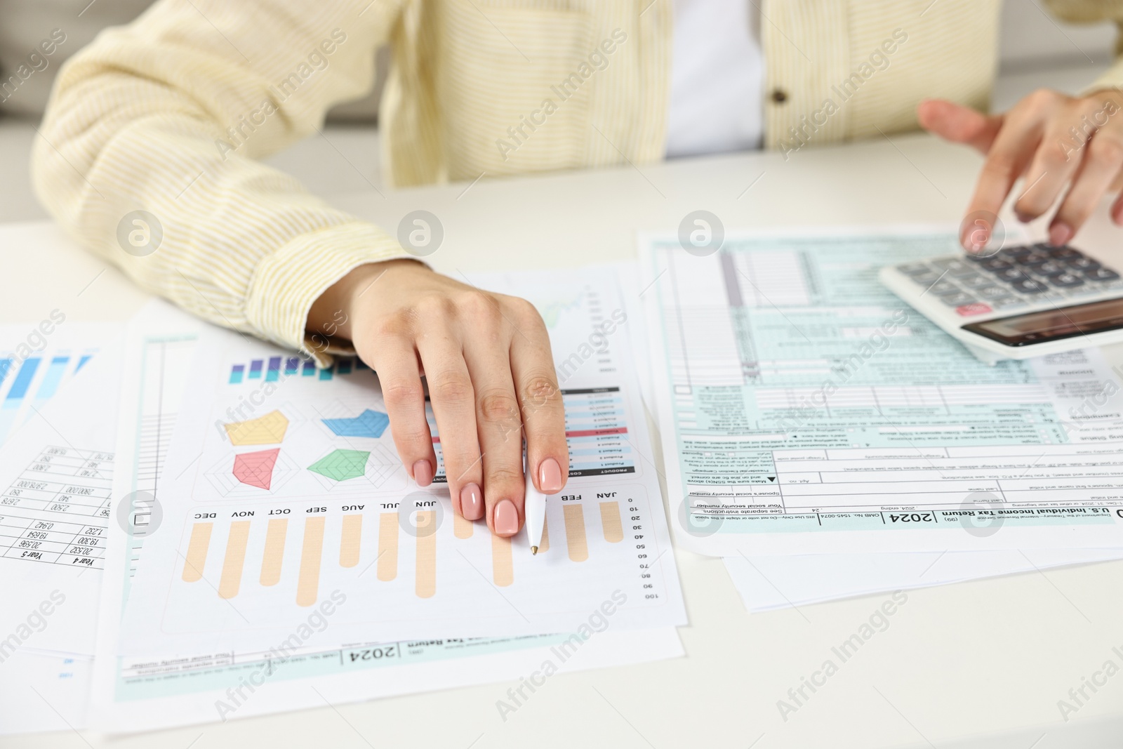 Photo of Budget planning. Woman with papers using calculator at white table, closeup