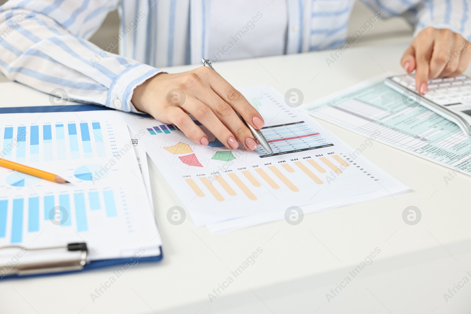 Photo of Budget planning. Woman with papers using calculator at white table, closeup