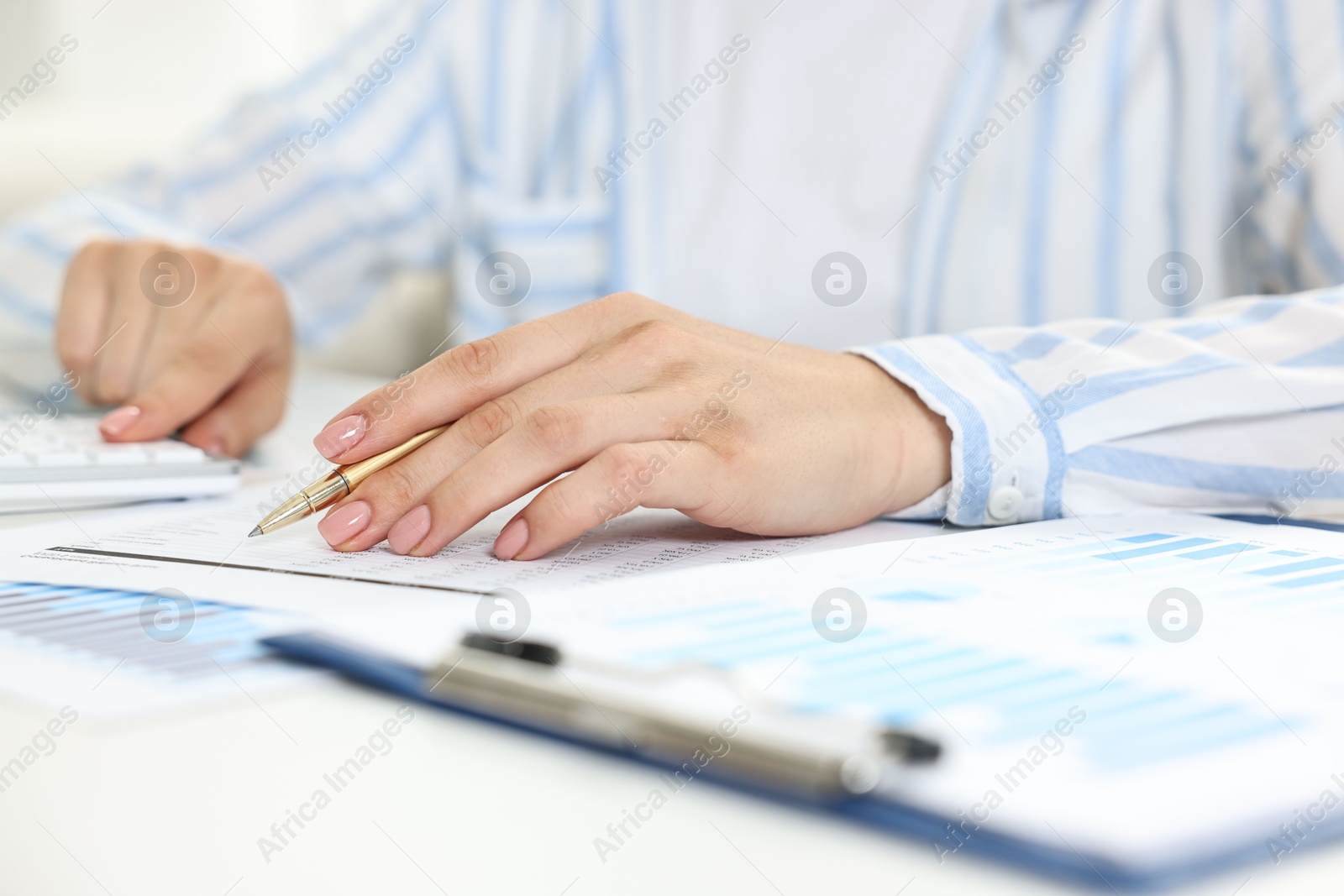 Photo of Budget planning. Woman with papers using calculator at white table, closeup